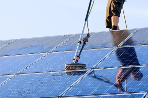 A technician using specialized tools to clean rooftop solar panels, ensuring maximum energy efficiency and optimal performance.